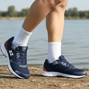 Tênis Abuzze Classic Running - Performance e Leveza 2026. Atleta praticando corrida na orla de um lago ao pôr do sol, usando Tênis Abuzze Classic Running Azul Marinho e Laranja - No Pé durante Corrida.