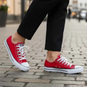 Tênis All Star feminino escolha o seu look. Pessoa caminhando em rua de paralelepípedo usando Tênis All Star Converse Urban Vermelho e calça preta.