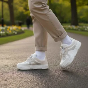 Tênis Feminino Casual Milano lindo. Pessoa caminhando em um parque usando o Tênis Milano na cor branca com detalhes em bege claro, combinado com calça de sarja bege.